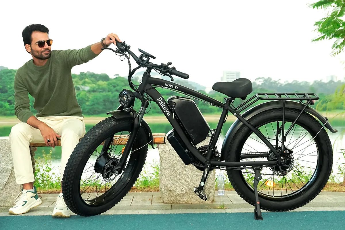 Person sitting beside a green fat-tire electric bike in an outdoor product photograph